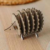 A small, wooden hedgehog-shaped coaster holder made of wood and felt sits on a light wooden table with a woven placemat in the background, adding a charming touch to your home decor.